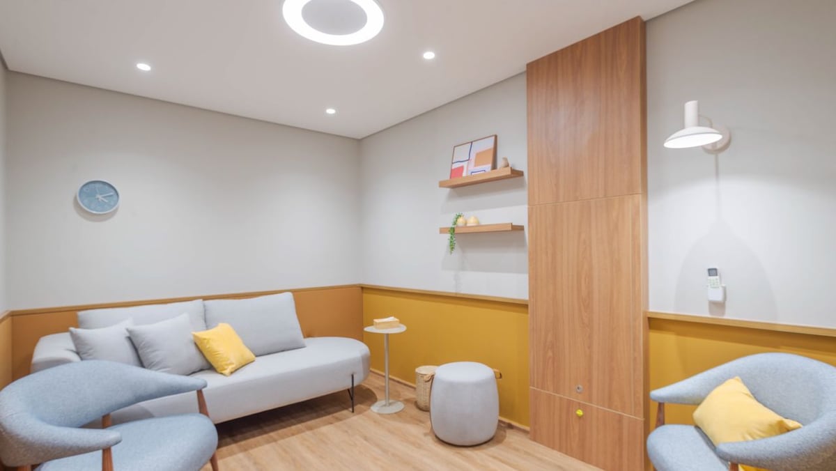 Sala de atendimento com sofá claro, poltronas e iluminação suave.